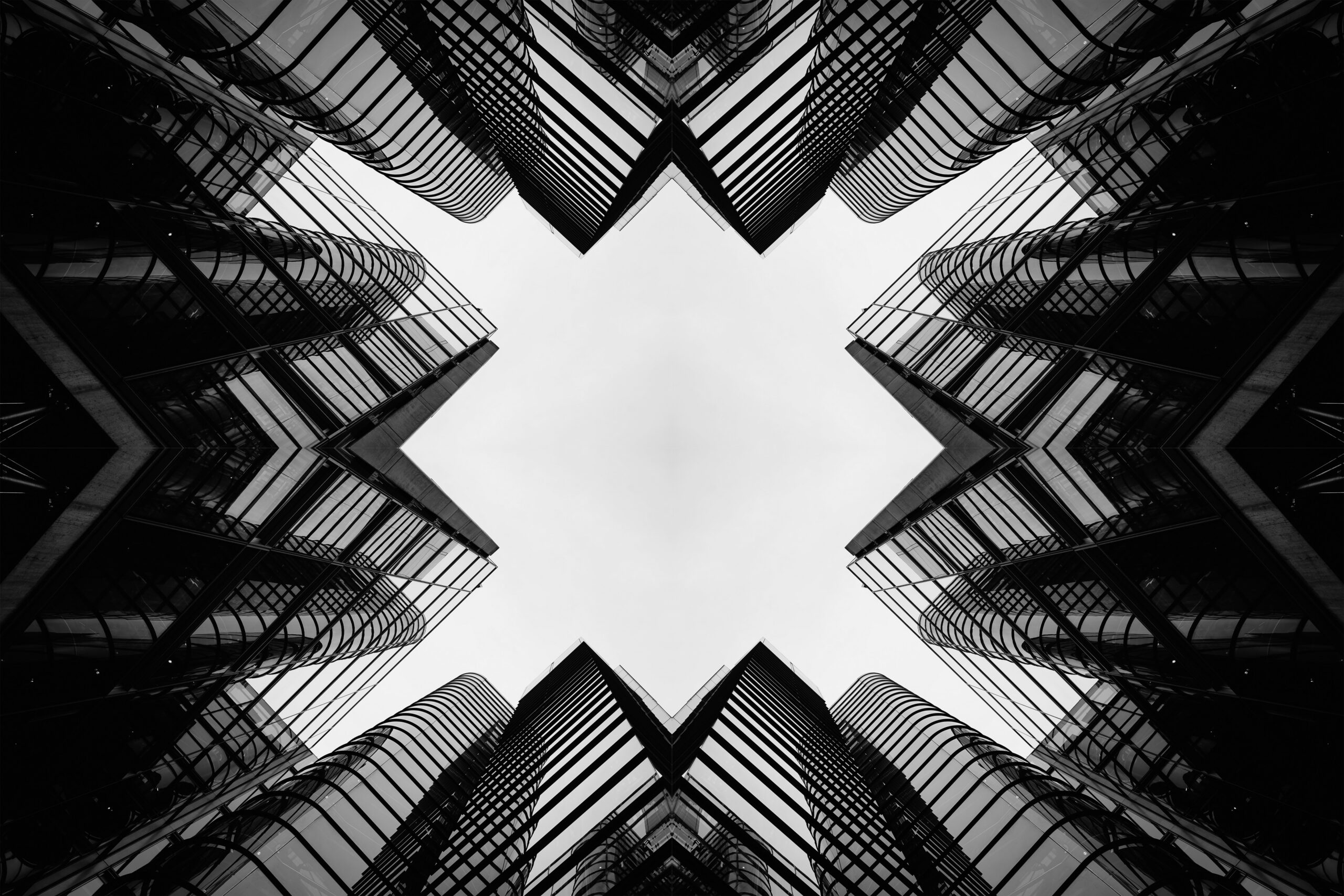 Black-and-white photo of converging skyscrapers seen from ground level, creating a dramatic inward perspective.
