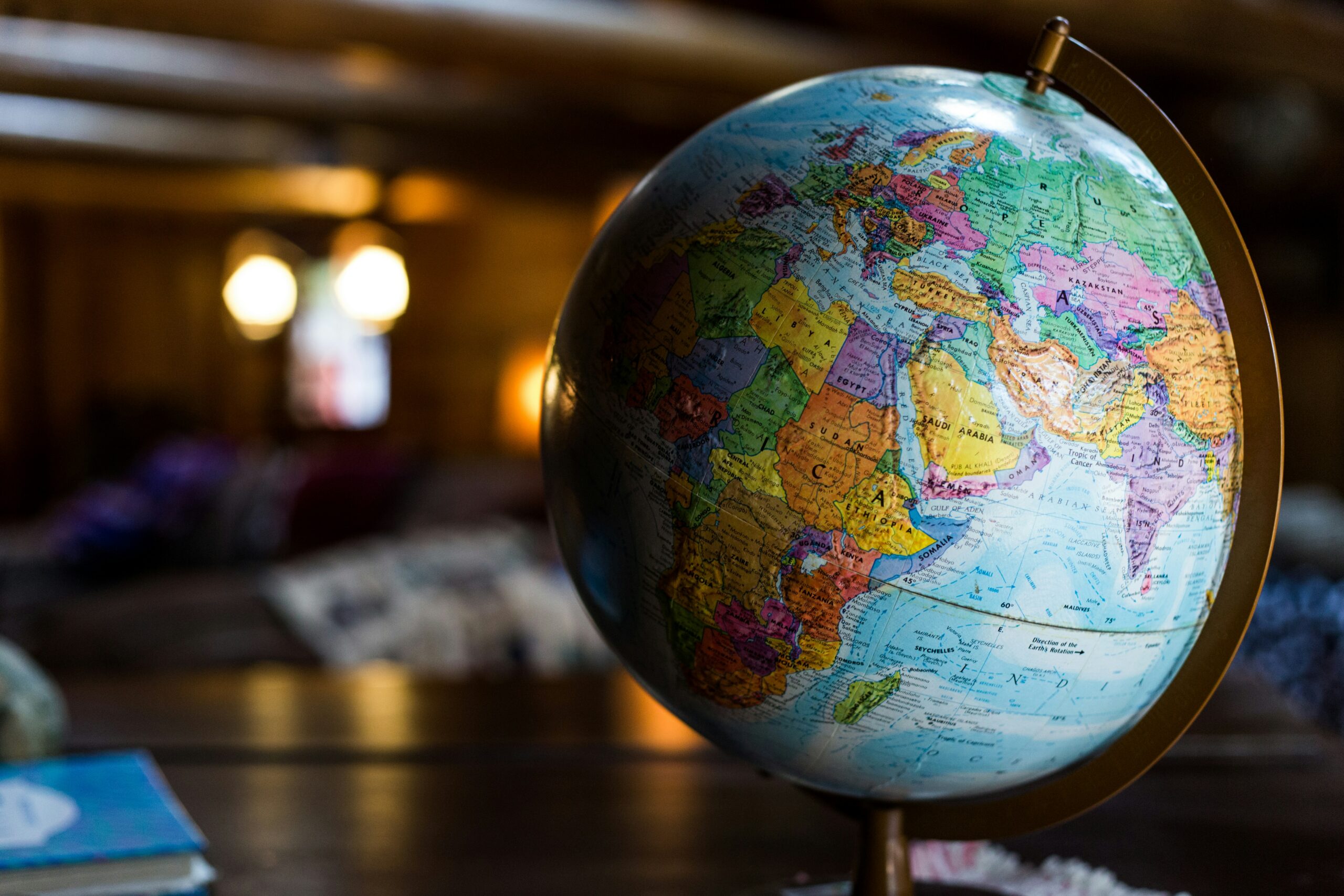 kyle-glenn-nXt5HtLmlgE-unsplash - AEGIS LAW - AEGIS LAW Globe on a stand in a dimly lit room, showing Africa and Europe with warm background lights behind it.